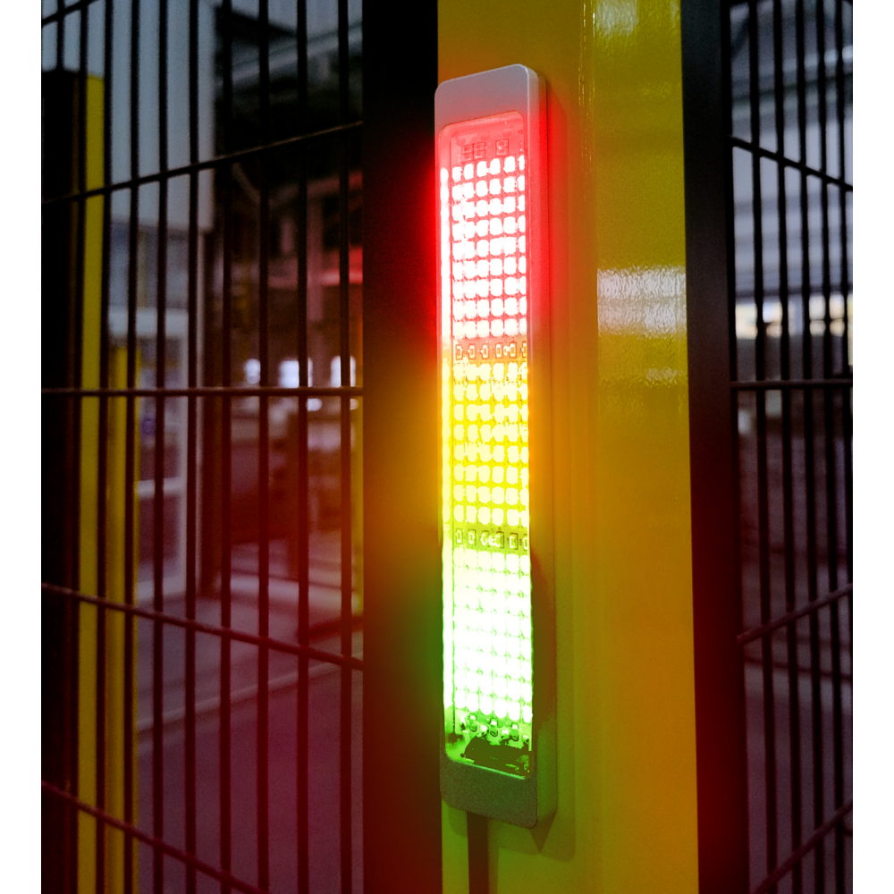Vertically mounted SL2 indicator light on yellow metal post showing red, yellow, and green illuminated segments with a metal grid fence in the background.