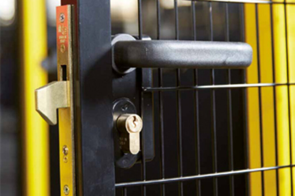 Close-up view of a black metal gate with a built-in lock and black handle.